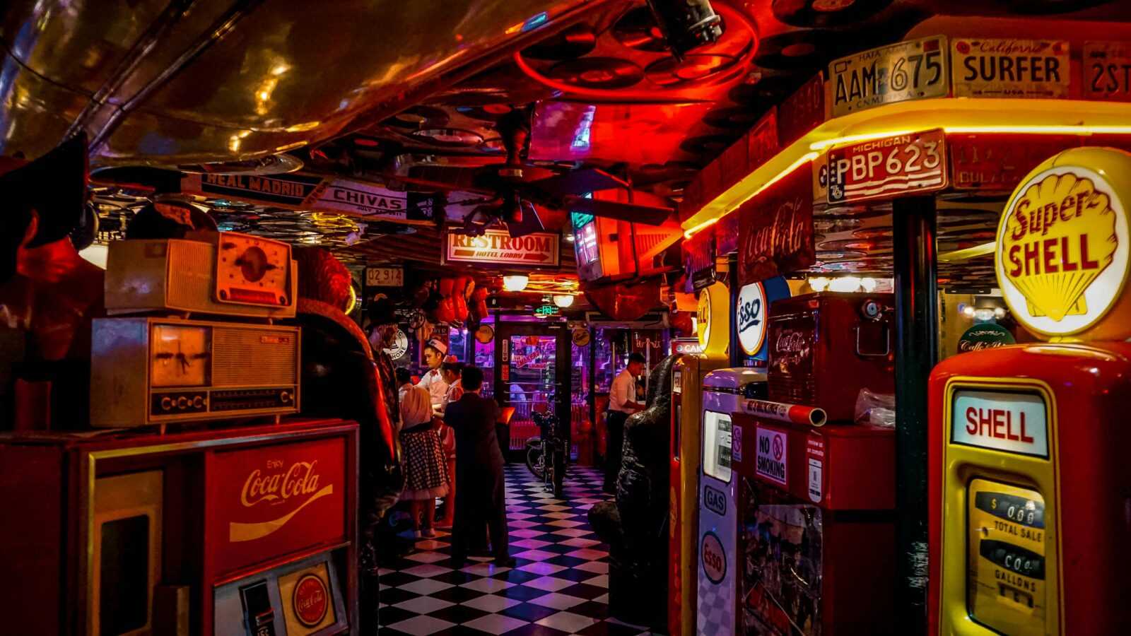 Vintage arcade bar with retro signs, people, and neon lights.